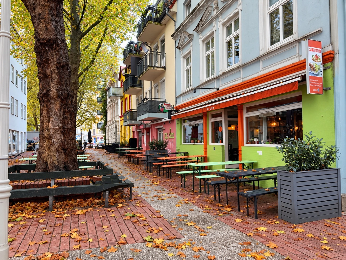 Altbauten, Bäume und Außengastronomie an einer Straße in Hamburg-Ottensen.